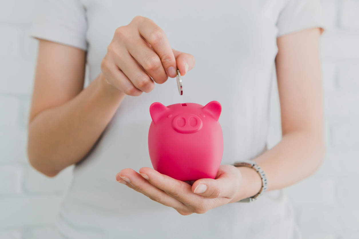 Woman's hand placing coin into piggy bank