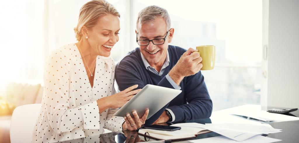 Happy couple reviewing documents on their electronic device Happy couple reviewing documents on tablet