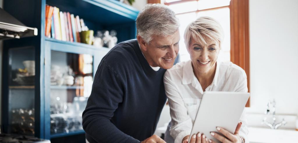 Reading tablet Middled aged couple in the kitchen reading tablet