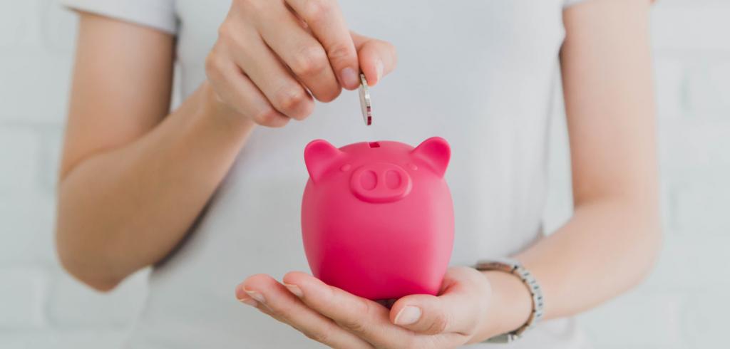 Woman's hand placing coin into piggy bank