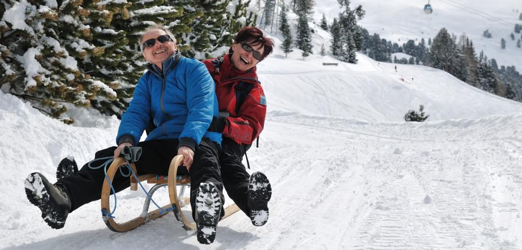 snow sledding man and woman snow sledding