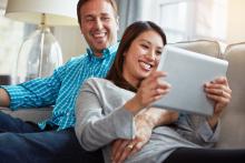Young couple on couch using tablet