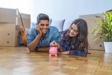Un jeune couple qui mettent une piece de monnaie dans une tirelire